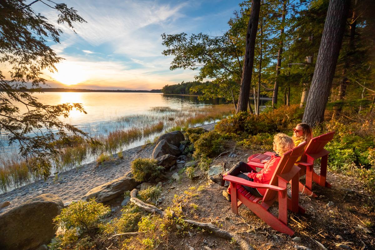 Two people sitting on chairs overlooking sunset over the water