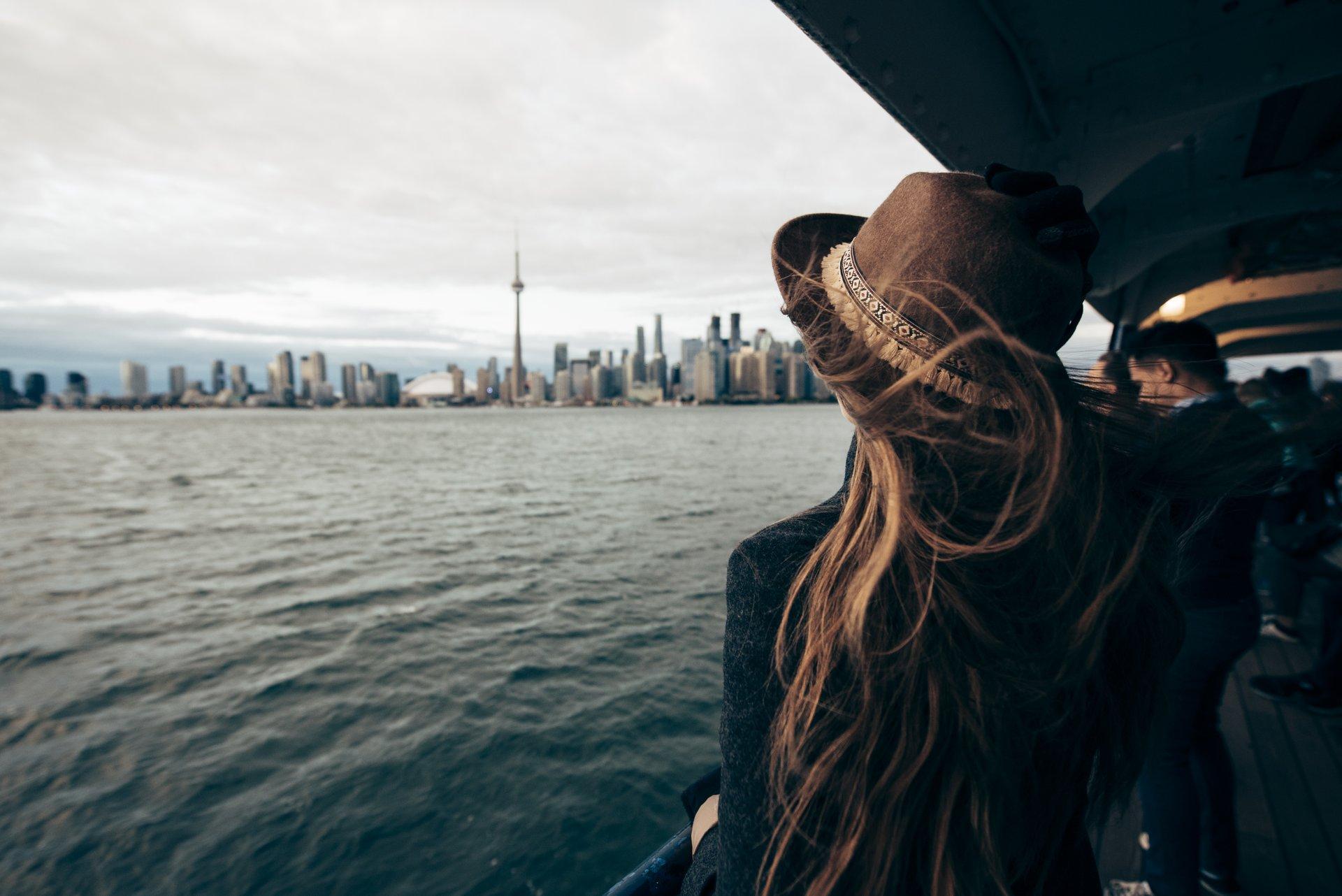 women on ferry with hair blowing in the wind looking at toronto