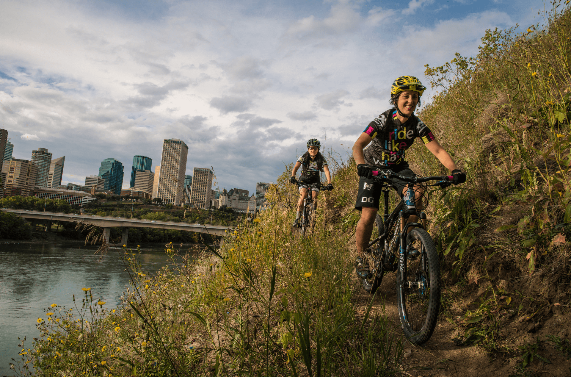 Two bikers ride alongside the Edmonton Valley River