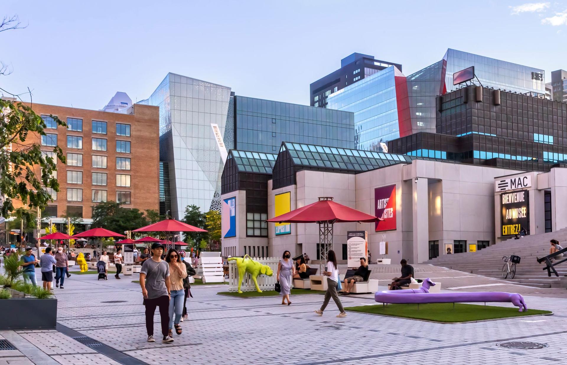 people walking past the outside of the place des arts building in quebec