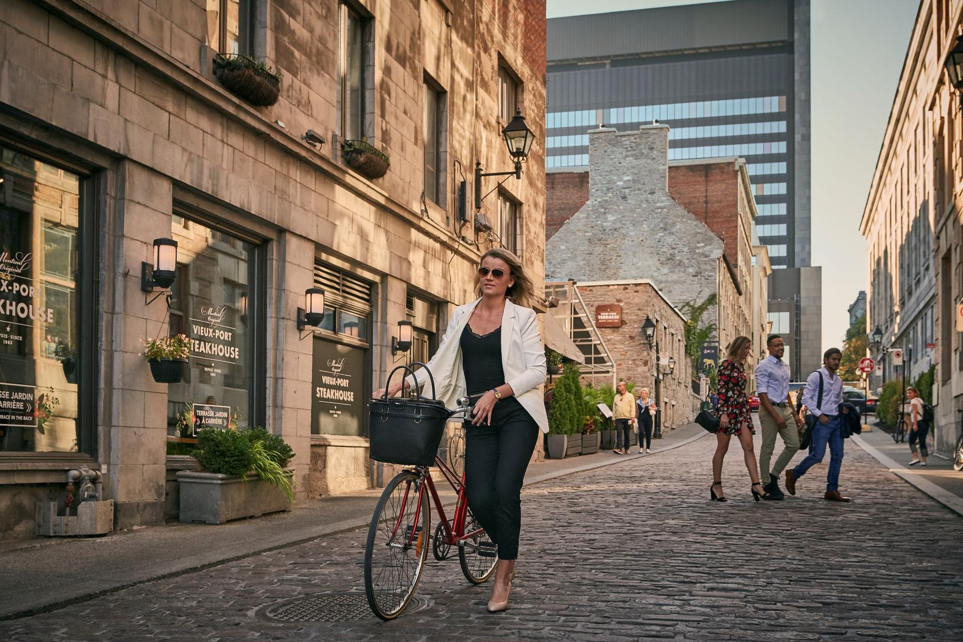 person walking their bike down a cobblestone street