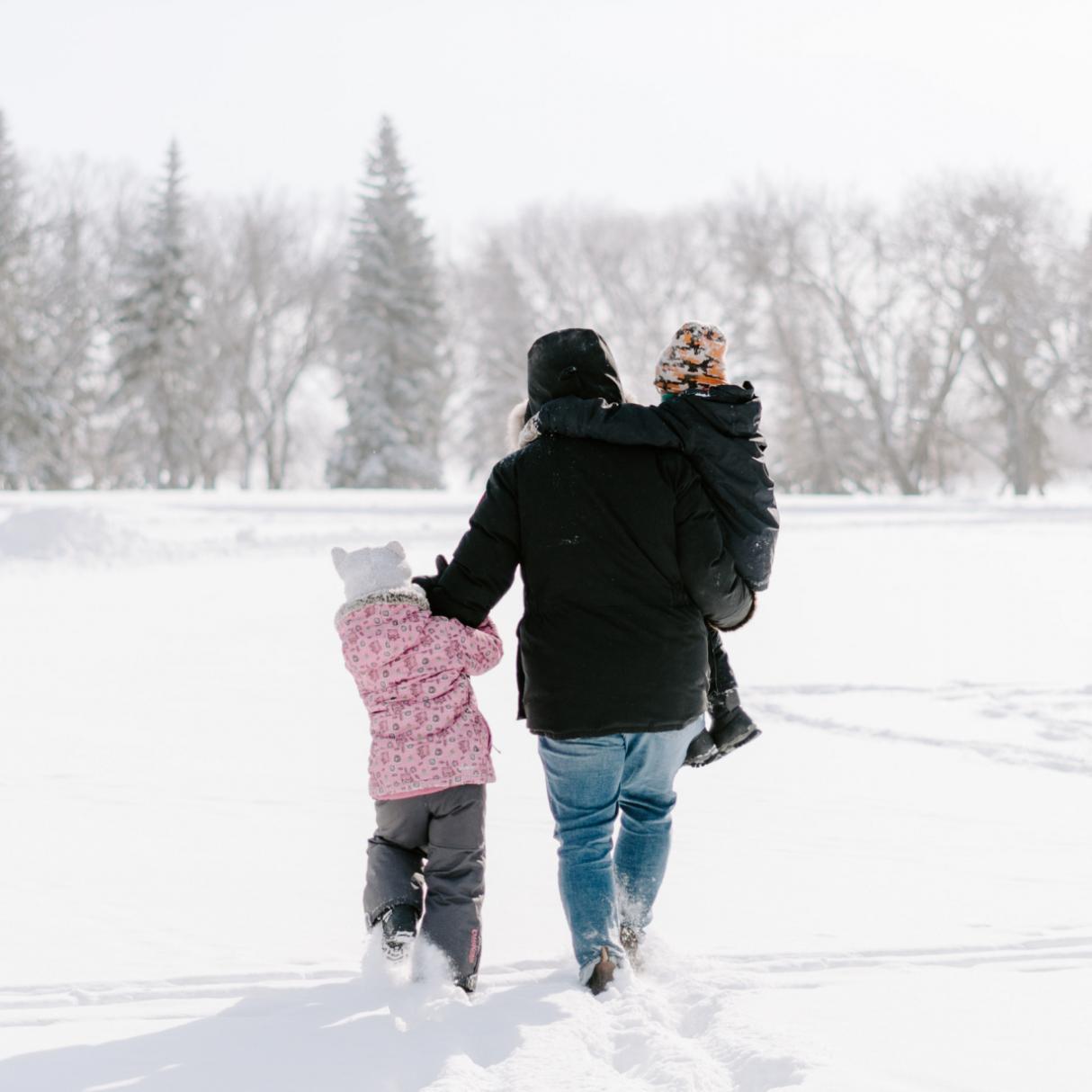 A family in snow gear walks across a snowy field