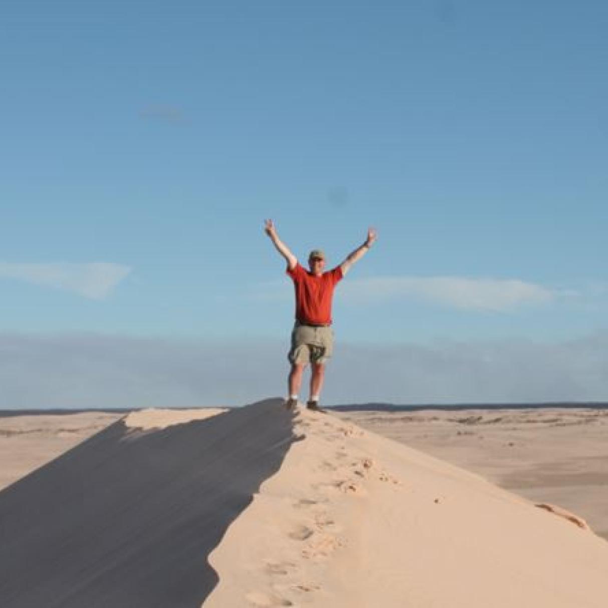 Guy standing on top of sand dune